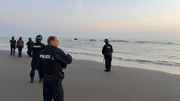 French police officers look on as migrants in Dunkirk, France, prepare to cross the English Channel