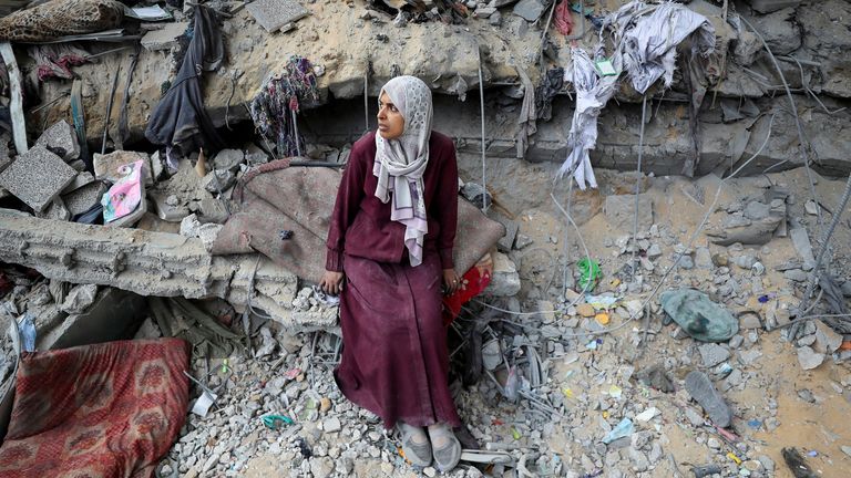 A Palestinian woman sits amid the damage at an UNRWA school sheltering displaced people. Pic: Reuters
