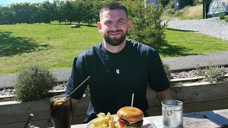 Greg Monks on holiday with a burger and fries in front on him