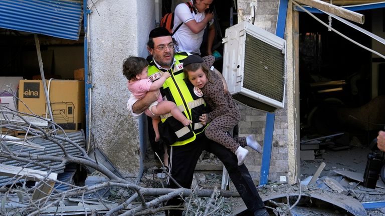 A rescue worker evacuates two children from the site where a missile launched from Iran struck in Haifa, Israel, Sunday, June 22, 2025. (AP Photo/Baz Ratner)
