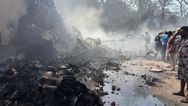 People stand around debris at the site of an airplane that crashed in India's northwestern city of Ahmedabad in Gujarat state, Thursday, June12, 2025. (AP Photo/Ajit Solanki)