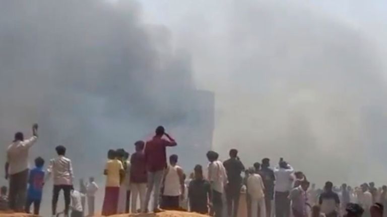 People watch smoke rising after an airplane crashed in Ahmedabad, Gujarat state, India, Thursday, June 12, 2025. (Mohan Nakum via AP)