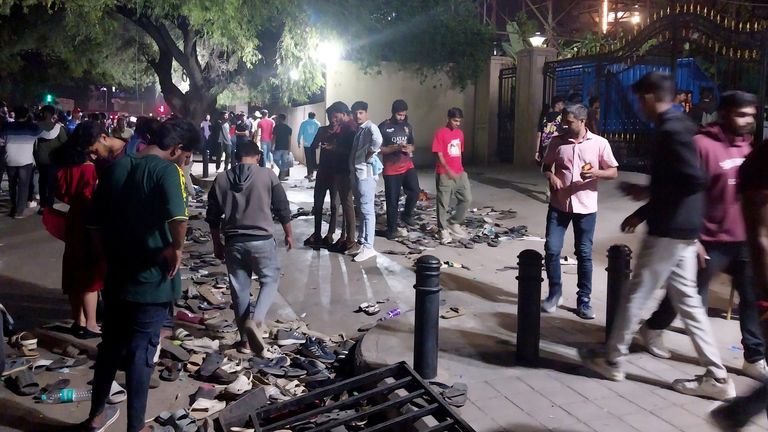 People walk past scattered shoes left behind following a stampede outside a cricket stadium in Bengaluru. Pic: Reuters