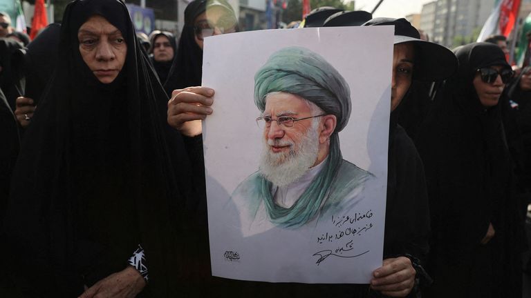 A woman holds a picture of Iran's Supreme Leader Ayatollah Ali Khamenei as she attends the funeral procession in Tehran.
Pic: Reuters