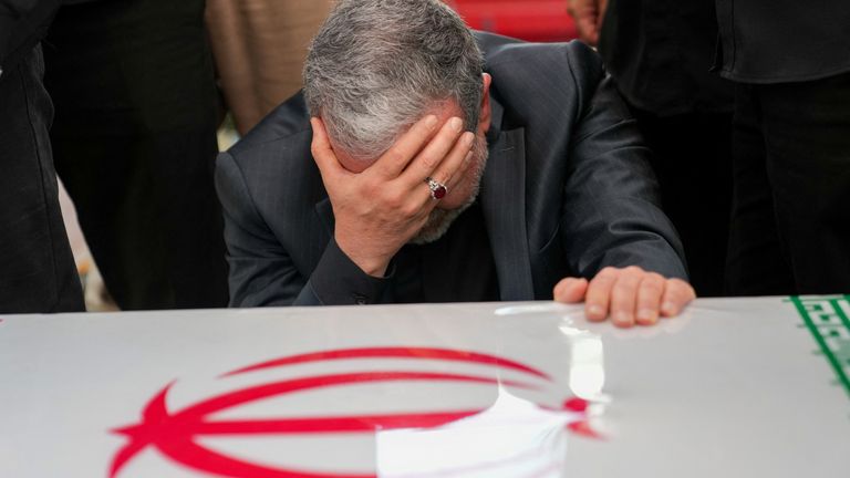 Foreign minister Abbas Araqchi covers his face and kneels in front of a coffin. Pic: Reuters
