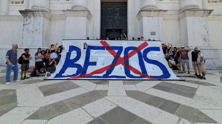Protesters stand with the sign that was put on the bell tower. Pic: Federica Toninelli