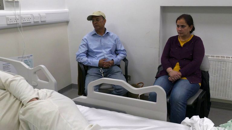 A man and woman sit by a hospital bed