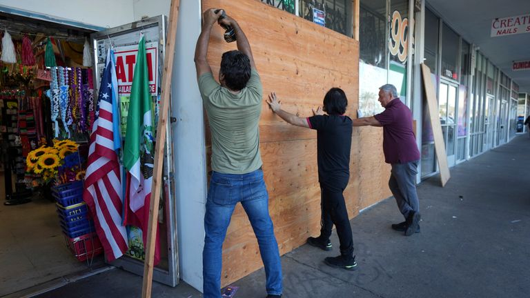Workers board up a store in Santa Ana. Pic: AP/Jae C. Hong