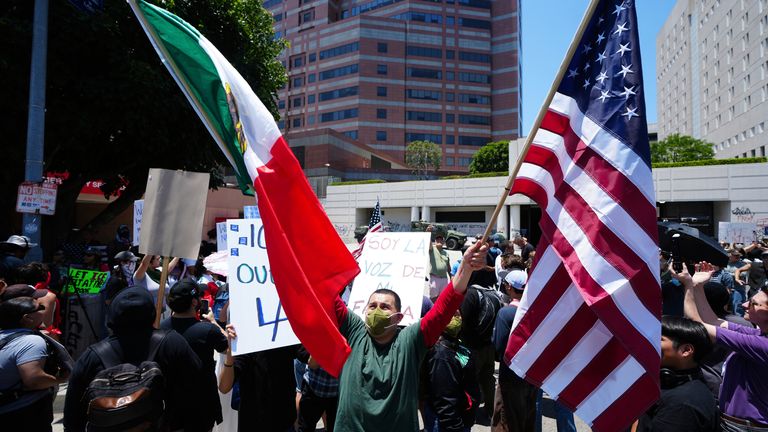 A man holds a Mexican flag, which has become synonymous with solidarity for migrants targeted in the raids. Pic: AP/Damian Dovarganes