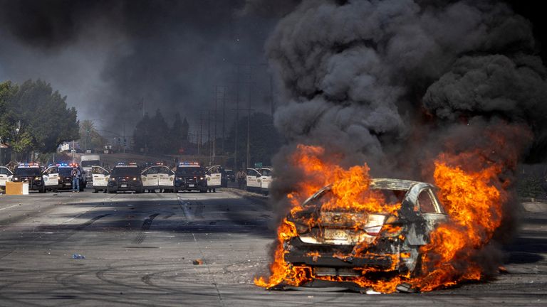 A car burns on Atlantic Boulevard in Paramount, Los Angeles on Saturday. Pic: Reuters
