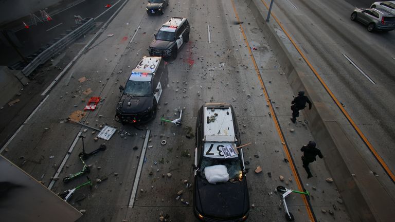 California Highway Patrol officers try to dodge rocks being thrown. Pic: AP/Ethan Swope