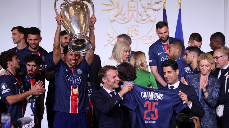 Fransa Cumhurbaşkanı Emmanuel Macron, oyuncuların kutladığı bir PSG forması düzenliyor. Pic: Reuters