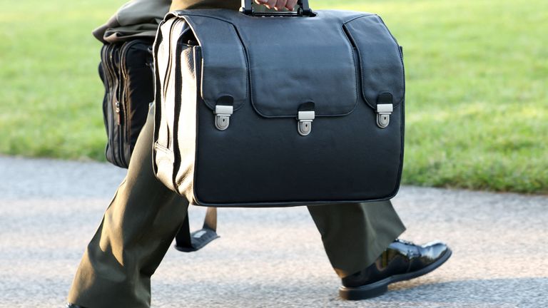 A White House military aide carries the so-called nuclear football as U.S. President Donald Trump boards Marine One.
Pic: PA