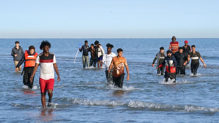 People thought to be migrants wade through the sea to board a small boat leaving the beach at Gravelines, France, in an attempt to reach the