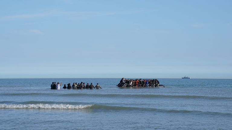 People thought to be migrants wade through the sea to board a small boat leaving the beach at Gravelines, France, in an attempt to reach the