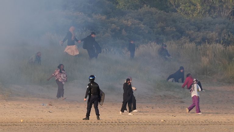 People thought to be migrants emerge from bushes on a beach in Gravelines, France, after French authorities had fired tear gas. Picture date