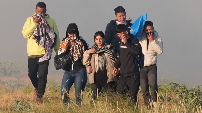 People thought to be migrants emerge from bushes on a beach in Gravelines, France, after French authorities had fired tear gas. Picture date