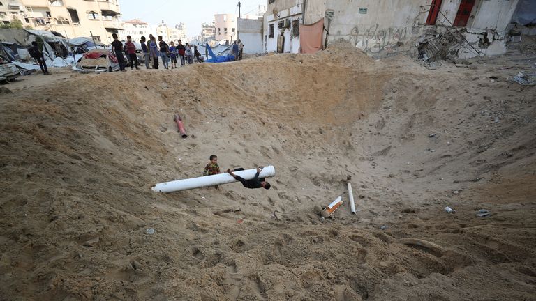 Palestinians gather at the site of a tent camp that was hit by an Israeli strike.
Pic: Reuters/Mahmoud Issa