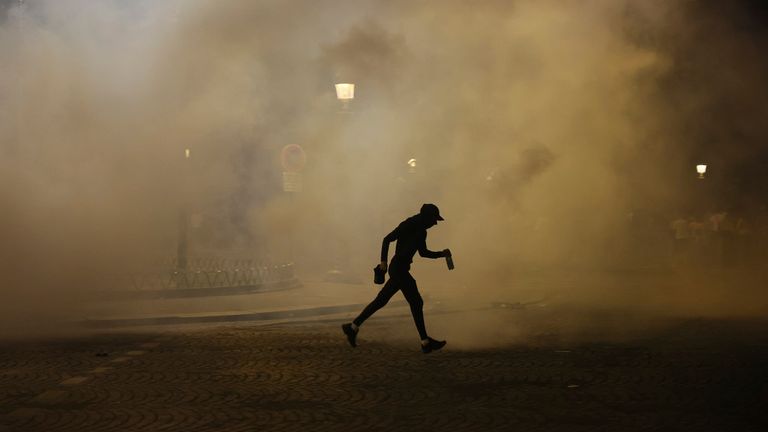 A man walks past teargas during incidents after the Champions League final soccer match between Paris Saint-Germain and Inter Milan. Pic: AP