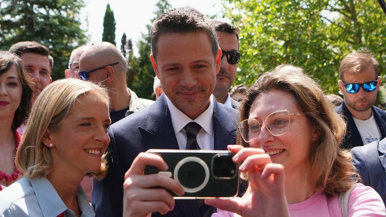 Rafal Trzaskowski poses for a selfie and leaves a polling station with his wife Malgorzata Trzaskowska. Pic: AP