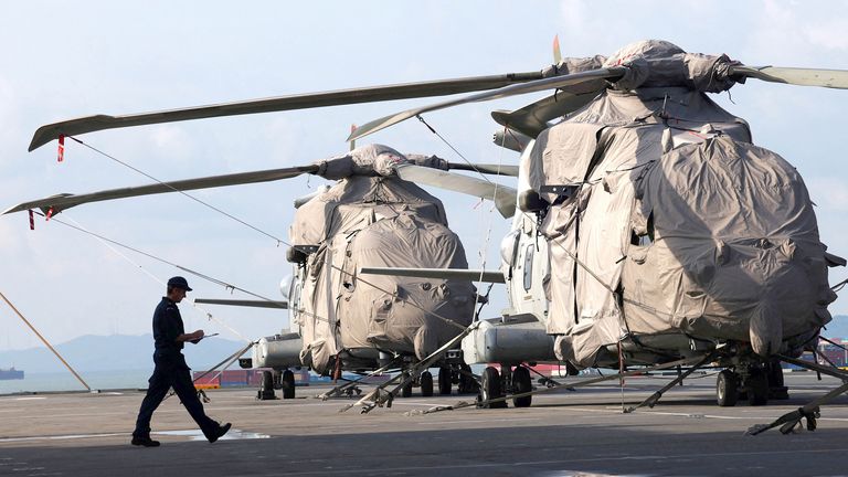 A serviceman passes Merlin helicopters onboard HMS Prince of Wales aircraft carrier at Marina Bay Cruise Centre in Singapore.
Pic: Reuters
