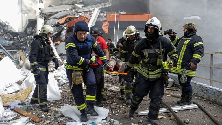 Rescuers carry away an injured resident after the first wave of Russia's attack on Kharkiv.
Pic: Reuters/Sofiia Gatilova