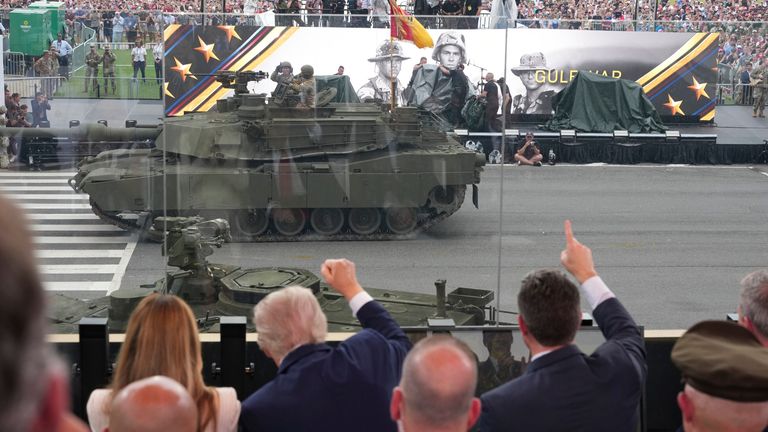 President Trump raises his fist as a tank passes. Pic: AP