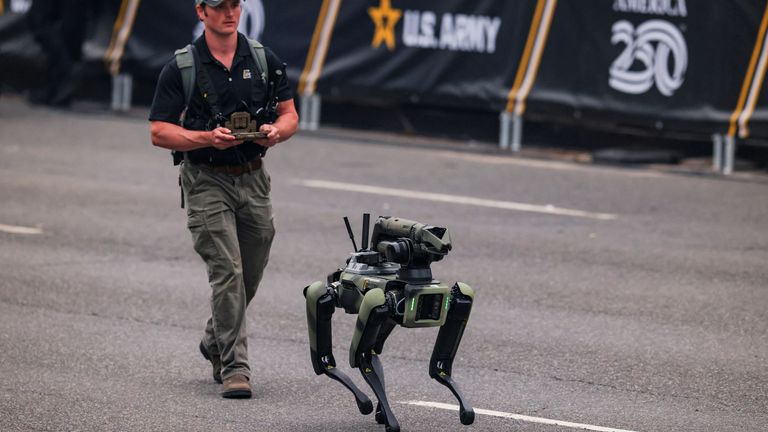 A man in tactical gear controls a 'dog' type robot. Pic: Reuters