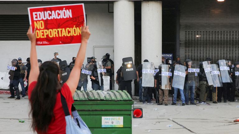 A protester holds up a sign to police outside the Los Angeles Federal Building in Los Angeles on Friday. Pic: Reuters