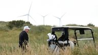 Donald Trump walks backdropped by wind turbines during an opening ceremony for the Trump International Golf Links golf course. Pic: AP