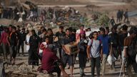 Palestinians carry aid packages near the GHF distribution centre in Khan Younis. Pic: AP/Abdel Kareem Hana