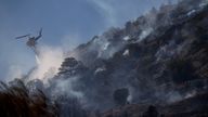 A firefighting helicopter makes a water drop during a wildfire in the town of Koropi, near Athens. Pic: Reuters