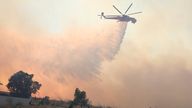 A helicopter drops water during a wildfire, in the northwestern suburb of Kryoneri, in Athens, Greece, Saturday, July 26, 2025. (AP Photo/Yorgos Karahalis)