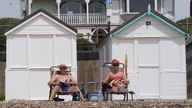 Two people sit on sun loungers beside the beach huts on the seafront in Southend-on-Sea, Essex. Pic: PA