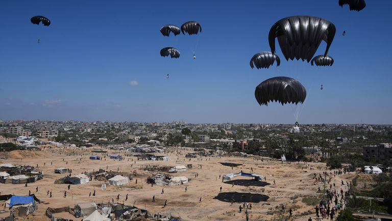 Palestinians rush to collect humanitarian aid airdropped in central Gaza. Pic: AP