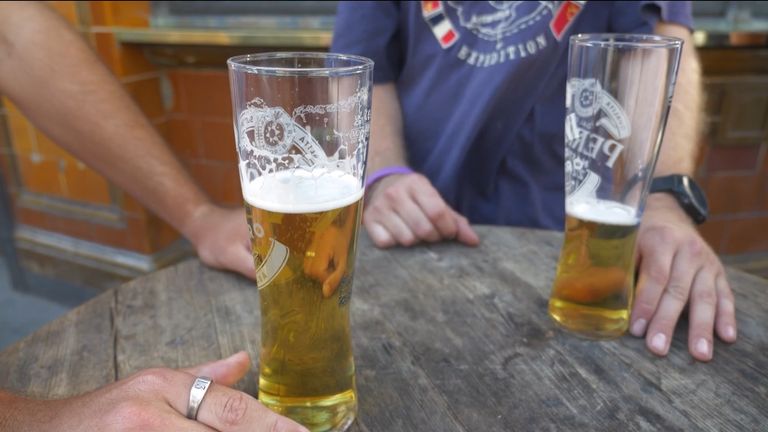 Two pints of beer sitting on a table outside of a pub