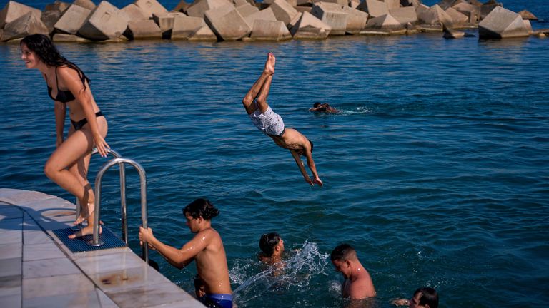 Swimmers jump into the water on a hot day in Barcelona, Spain, Tuesday, July 1, 2025. (AP Photo/Emilio Morenatti)