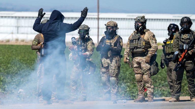 Federal immigration agents toss tear gas at protesters during a raid in the agriculture area of Camarillo, Calif