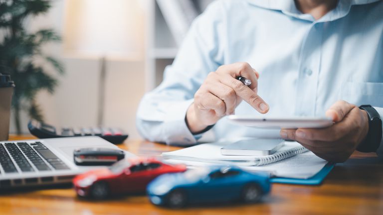 Toy Car In Front Of Businessman Calculating Loan. Saving money for car concept, trade car for cash concept, finance concept.