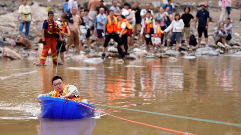 A man sits in a plastic boat to move to safety after heavy rainfall flooded the Huairou district of Beijing. Pic: Reuters