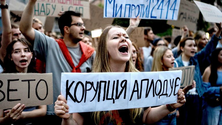  A woman holds a banner reading "Corruption Applauds". Pic: AP/ 