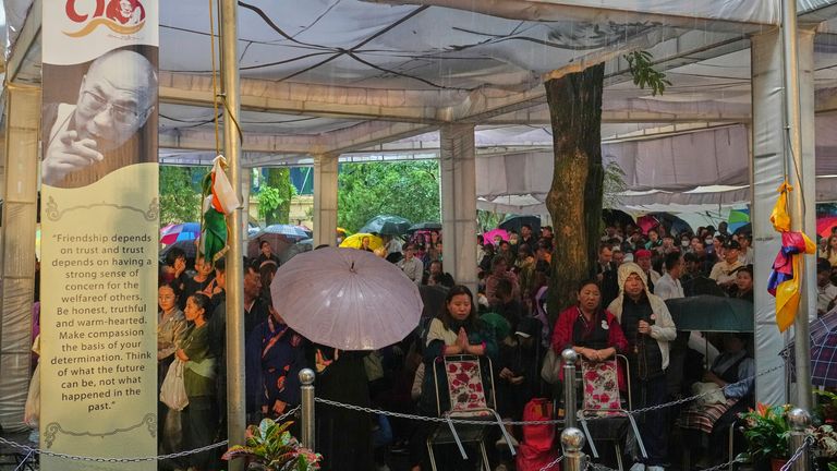 Devotees wait in the rain for the arrival of the Dalai Lama at an event celebrating his birthday. Pic: AP/Ashwini Bhatia