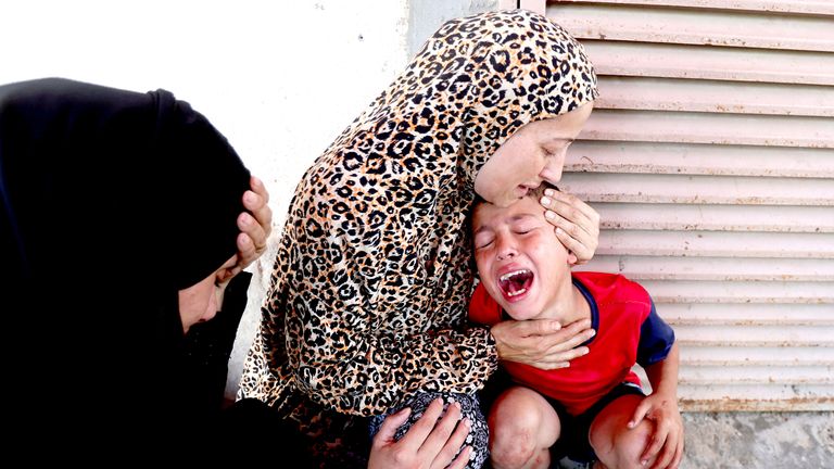 A Palestinian woman comforts a child at  Al-Aqsa Martyrs Hospital following an Israeli strike, in Deir al-Balah.
Pic: Reuters