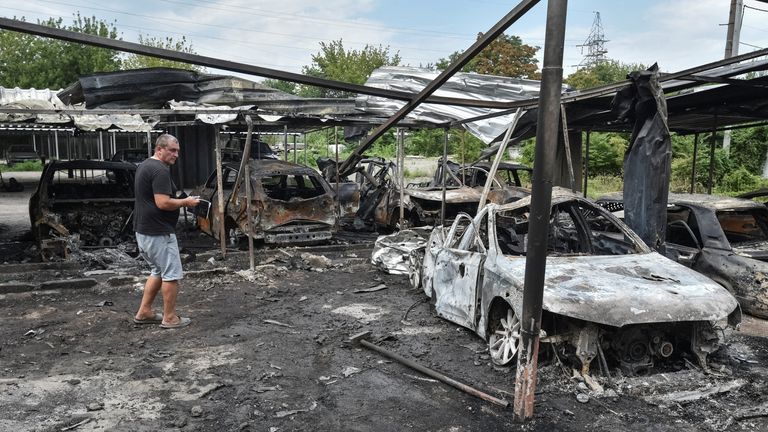 A man stands next to burned cars in Dnipro. Pic: Reuters