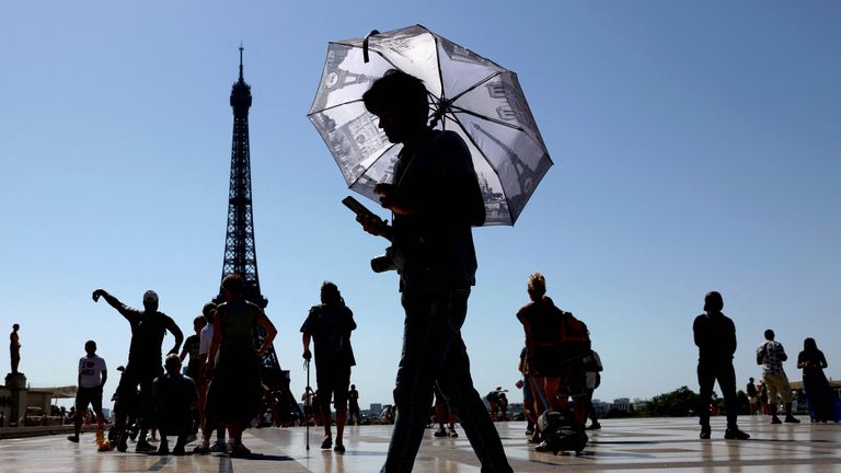 A fase mantém o guarda -chuva para proteger do pôr do sol ao canto de Trocadero, perto da Torre Eiffel. Reuters de imagens