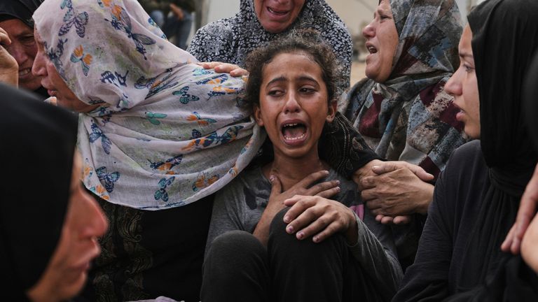 Lian Al-Za'anin, center, is comforted by relatives as she mourns the loss of her father, Rami Al-Za'anin, who was killed while heading to an aid distribution hub, at the morgue of the Shifa Hospital in Gaza City, on Thursday, July 3, 2025. (AP Photo/Jehad Alshrafi)