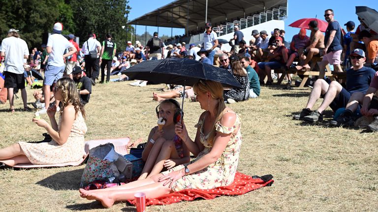 Halk üyeleri Batı Sussex Goodwood Hız Festivali'nde güneşte gölge için bir şemsiye kullanıyor. Pic: PA 