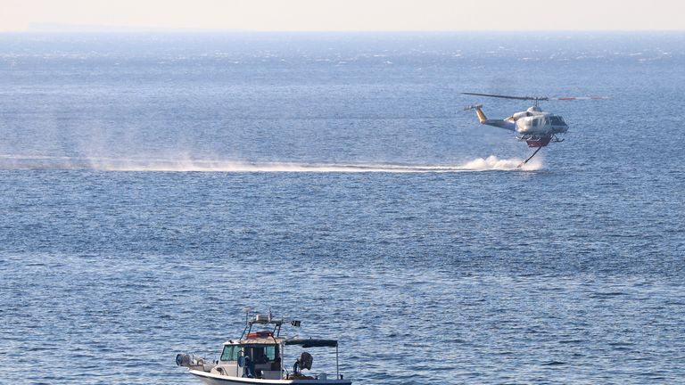 No bombeiro pega água do mar, quando um fogo ardente está quente perto do Leaptra, na ilha de Creta, na Grécia. Imagem: Reuters