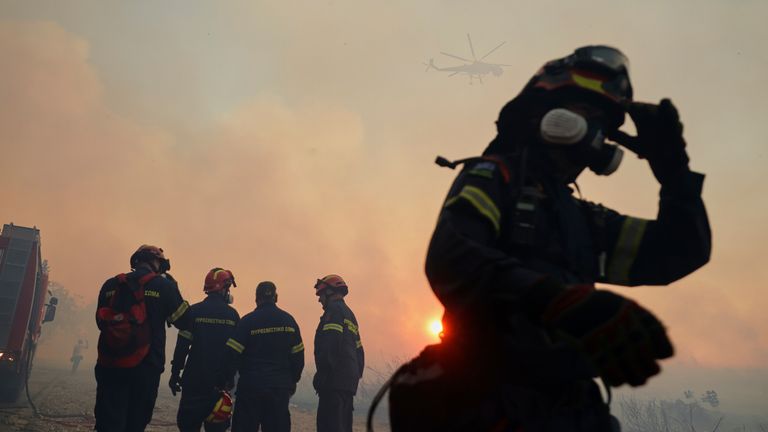 Firefighters try to extinguish the blazes as a helicopter flies during a wildfire, in the northwestern suburb of Kryoneri, in Athens, Greece, Saturday, July 26, 2025. (AP Photo/Yorgos Karahalis)