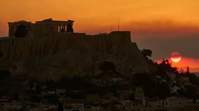 Słońce zachodzi za wzgórzem Acropolis, gdy dym z pobliskiego pożaru wypełnia niebo podczas fali upałów w Atenach, Grecji, sobota, 26 lipca 2025 r. (AP Photo/Petros Giannakouris)